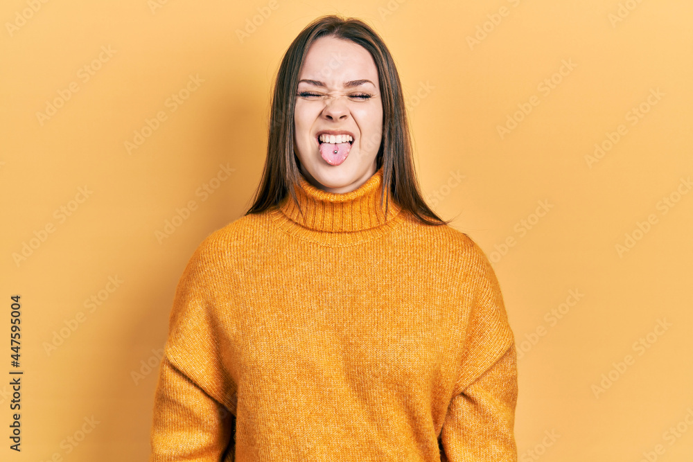 Young hispanic girl wearing casual clothes sticking tongue out happy with funny expression. emotion concept. Young hispanic girl wearing casual clothes sticking tongue out happy with funny expression. emotion concept.