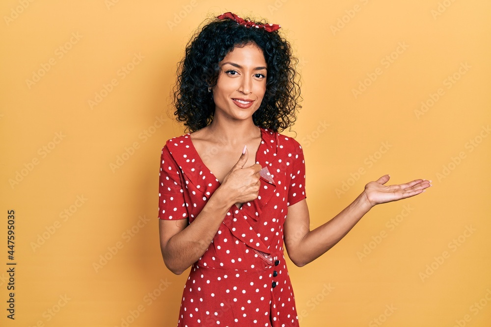 Young latin girl wearing summer dress showing palm hand and doing ok gesture with thumbs up, smiling happy and cheerful Young latin girl wearing summer dress showing palm hand and doing ok gesture with thumbs up, smiling happy and cheerful