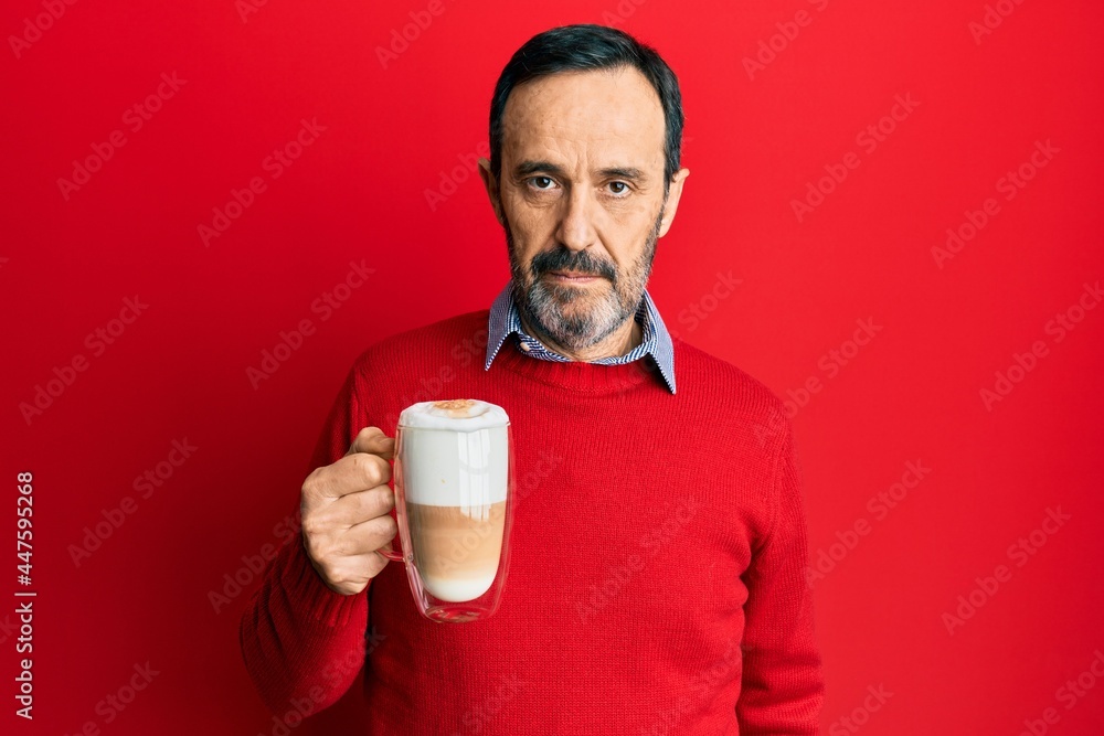 Middle age hispanic man drinking a cup of cappuccino coffee thinking attitude and sober expression looking self confident Middle age hispanic man drinking a cup of cappuccino coffee thinking attitude and sober expression looking self confident