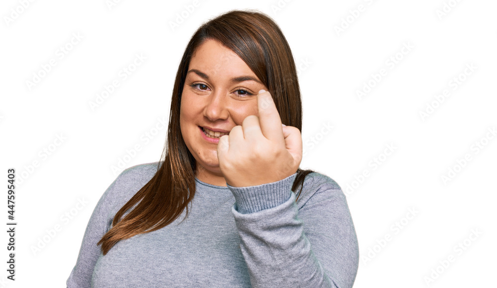 Beautiful brunette plus size woman wearing casual clothes beckoning come here gesture with hand inviting welcoming happy and smiling