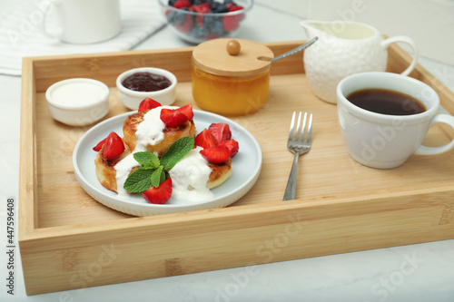 Delicious cottage cheese pancakes with fresh strawberries sour cream and mint served on wooden tray