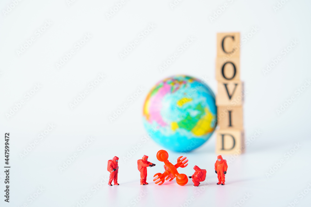 big virus with a team of special medical forces miniature figurines, the team preparing for action against dangerous deadly virus type ,world toy and Wooden cubes with words 'covid' 