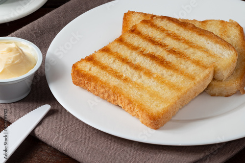 Toasted bread with butter on white plate.