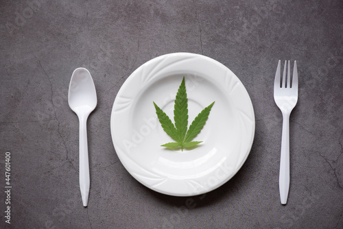 Cannabis leaf - marijuana leaves plant on white plate and spoon fork, cannabis food nature herb concept