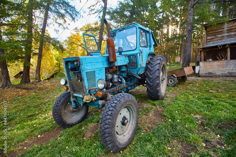 An old blue tractor stands in a farmyard An old blue tractor stands in a farmyard