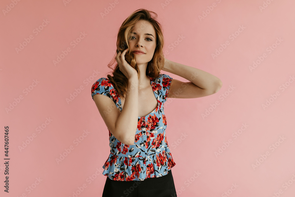 Beautiful curly woman in blue summer top playing her hair on isolated background. Trendy girl in floral clothes smiling.. Beautiful curly woman in blue summer top playing her hair on isolated background. Trendy girl in floral clothes smiling..