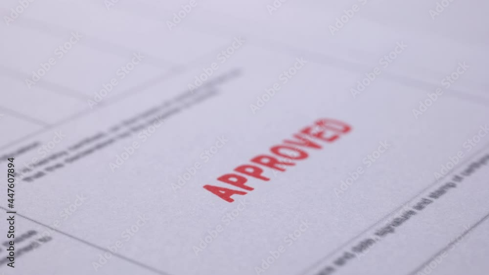 Business financial document with stamping message with rubber stamp. Closeup document marked with approved stamp Business financial document with stamping message with rubber stamp. Closeup document marked with approved stamp