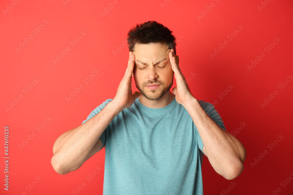 Man suffering from terrible migraine on red background Man suffering from terrible migraine on red background