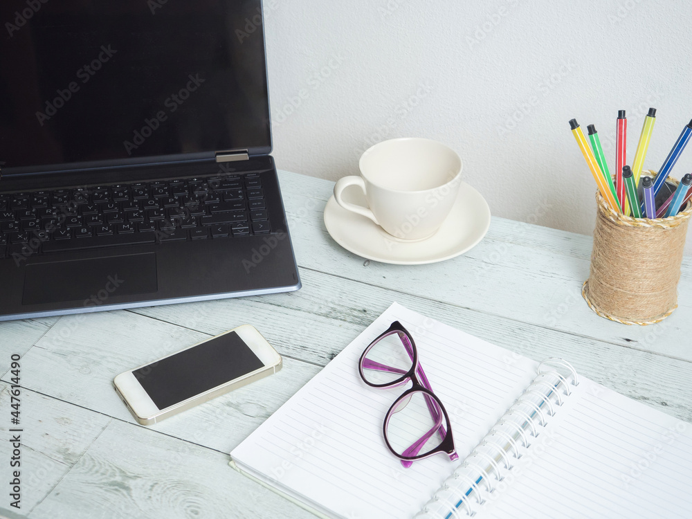Workspace on wood table,Laptop notebook glasses coffee cup and mobile phone on the table Workspace on wood table,Laptop notebook glasses coffee cup and mobile phone on the table
