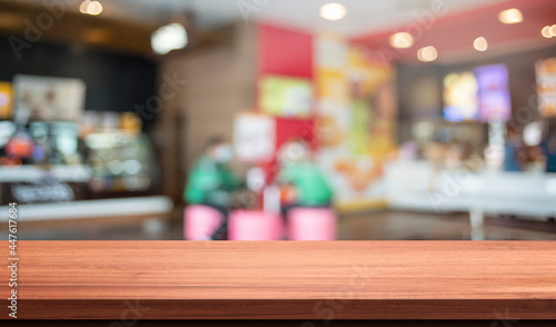 wood table in blurry background with fast food restaurant or coffee shop ,nature orange bokeh and sunlight in morning.