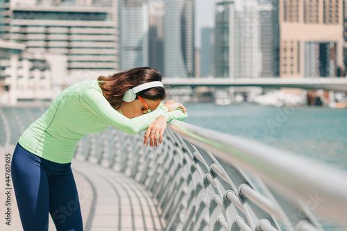 Fotografi Woman suffering from shortness of breath or asthma leans against a fence and res