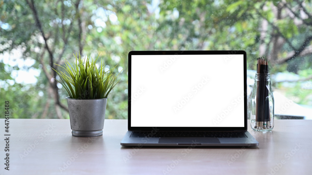 Computer laptop with blank display, houseplant and pencil holder on white table. Computer laptop with blank display, houseplant and pencil holder on white table.