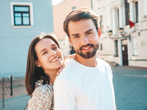 Smiling beautiful woman and her handsome boyfriend. Woman in casual summer clothes. Happy cheerful family. Female having fun. Couple posing on the street background.Hugging each other at sunset