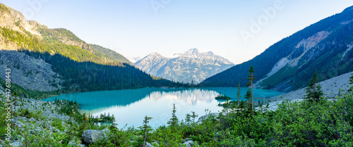 Emerald Upper Joffre Lake panorama with a mountain backdrop and tents on the shoreline in British Columbia, Canada