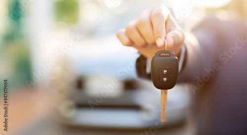 A man holding a car key in front of a car at a showroom