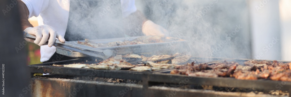 Chef prepares meat on grill in open air Chef prepares meat on grill in open air