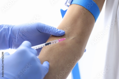 Gloved doctor injects patient into vein closeup