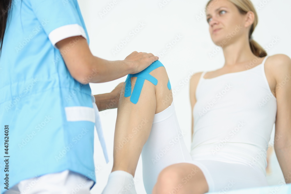 Doctor fixes kinesio tape on female leg Doctor fixes kinesio tape on female leg