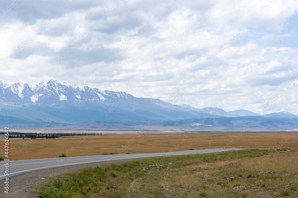snowy peaks of mountains and steppe on a background of cloudy sky snowy peaks of mountains and steppe on a background of cloudy sky