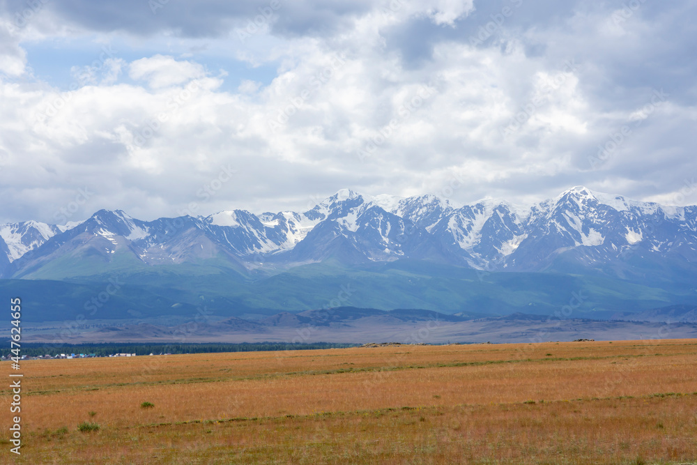 snowy peaks of mountains and steppe on a background of cloudy sky