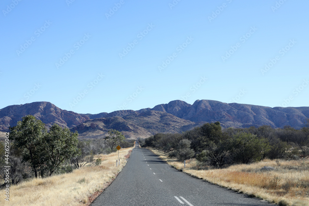 The stunning MacDonnell Ranges, outside Alice Springs, Northern Territory, Australia.  With long roads and open plains with distant mountains.
