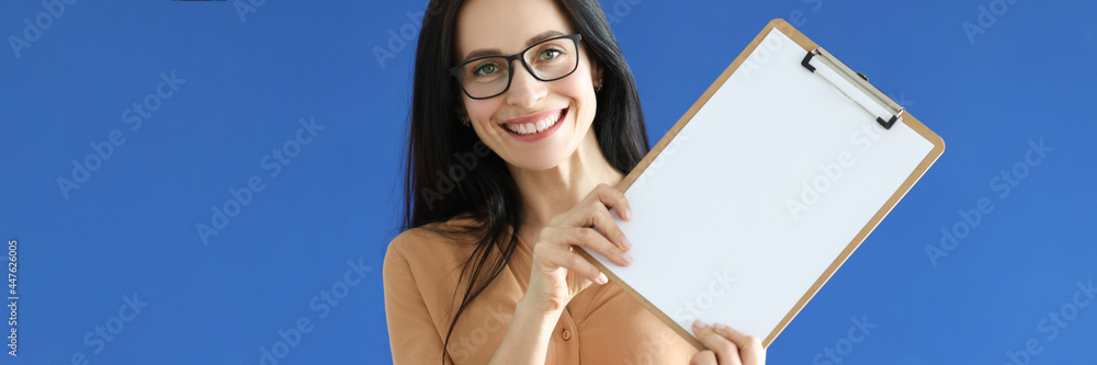 Woman with glasses holding blank sheet of paper in her hands Woman with glasses holding blank sheet of paper in her hands