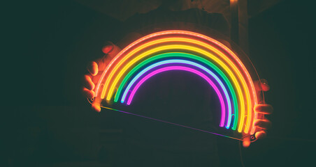 Guy holds neon led rainbow in hands in the night