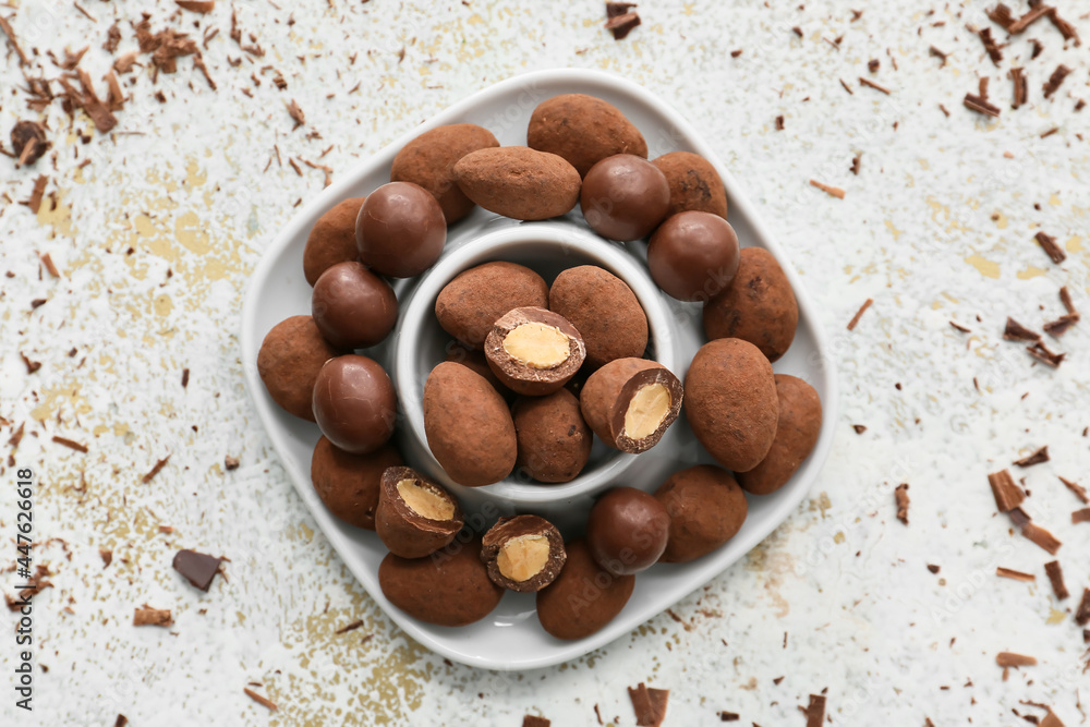 Fototapeta premium Bowl with tasty chocolate candies on grunge background