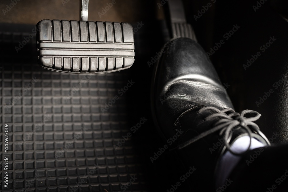 A man in leather shoes is stepping on the accelerator of a car. A man in leather shoes is stepping on the accelerator of a car.