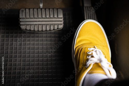 A man in yellow sneakers is stepping on the accelerator of a car. photo