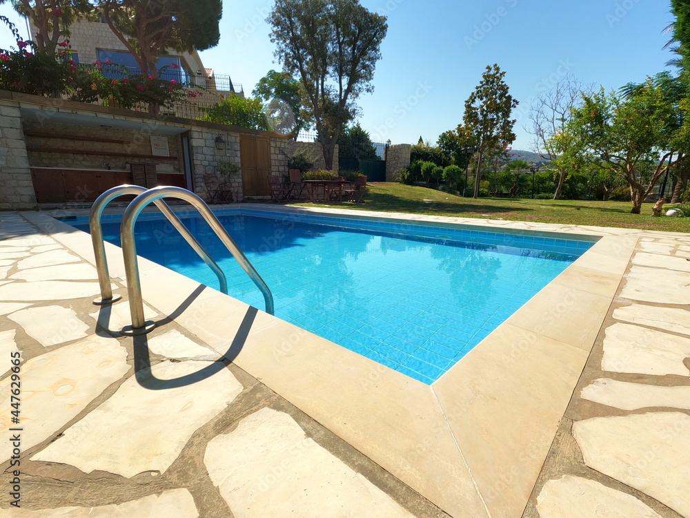 Beautiful old swimming pool in summer season. Blue tiles. Garden and pool view. Vacation time Beautiful old swimming pool in summer season. Blue tiles. Garden and pool view. Vacation time