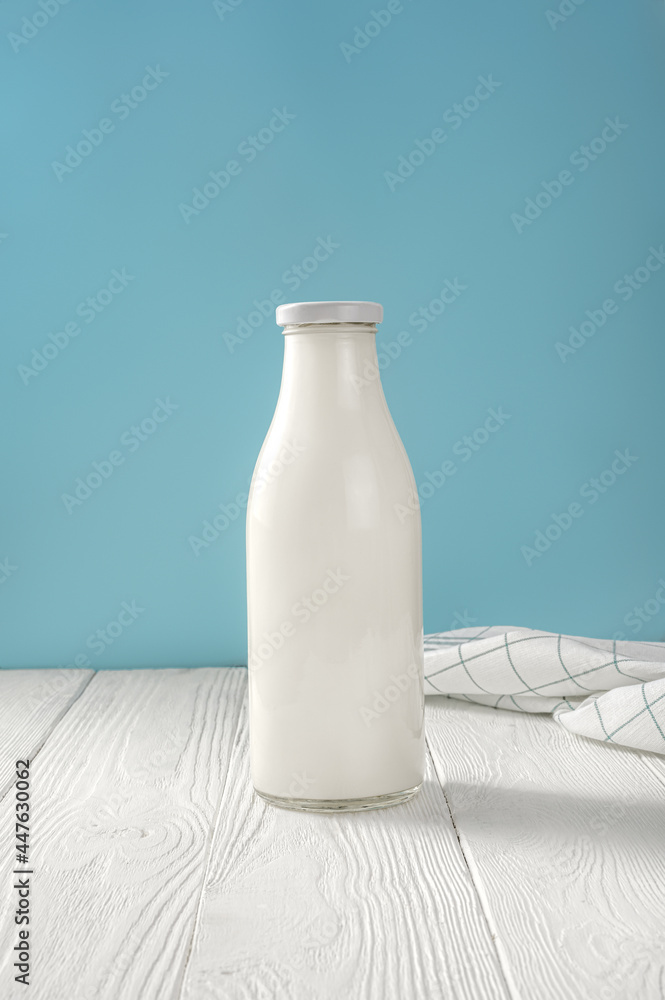 Milk in glass bottle and napkin on white wooden table. Bottle of milk on  blue background with copy space. World milk day. Stock Photo | Adobe Stock