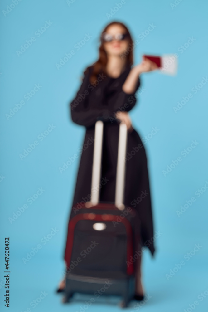 Woman in black coat suitcase sunglasses vacation blue background Woman in black coat suitcase sunglasses vacation blue background