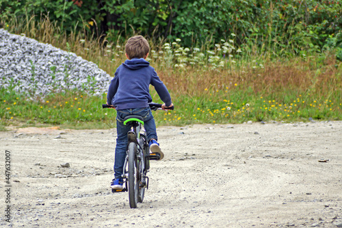 Fototapeta Naklejka Na Ścianę i Meble -  A boy rides a bicycle on a village street
