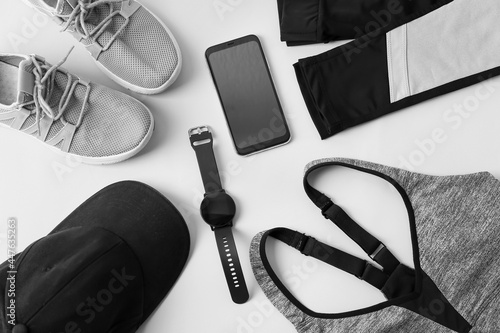 Sportswear, smart watch and mobile phone on light background