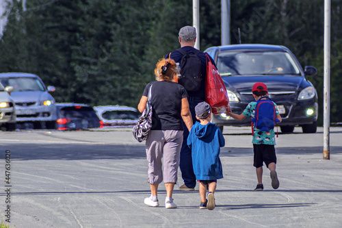 Grandfather, grandmother and two grandchildren walk along the sidewalk on a summer day