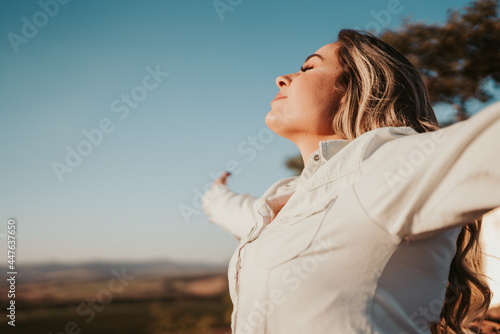 Latin woman at sunset breathing fresh air raising arms. photo
