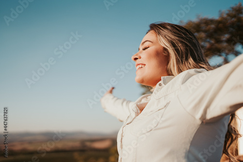 Latin woman at sunset breathing fresh air raising arms.