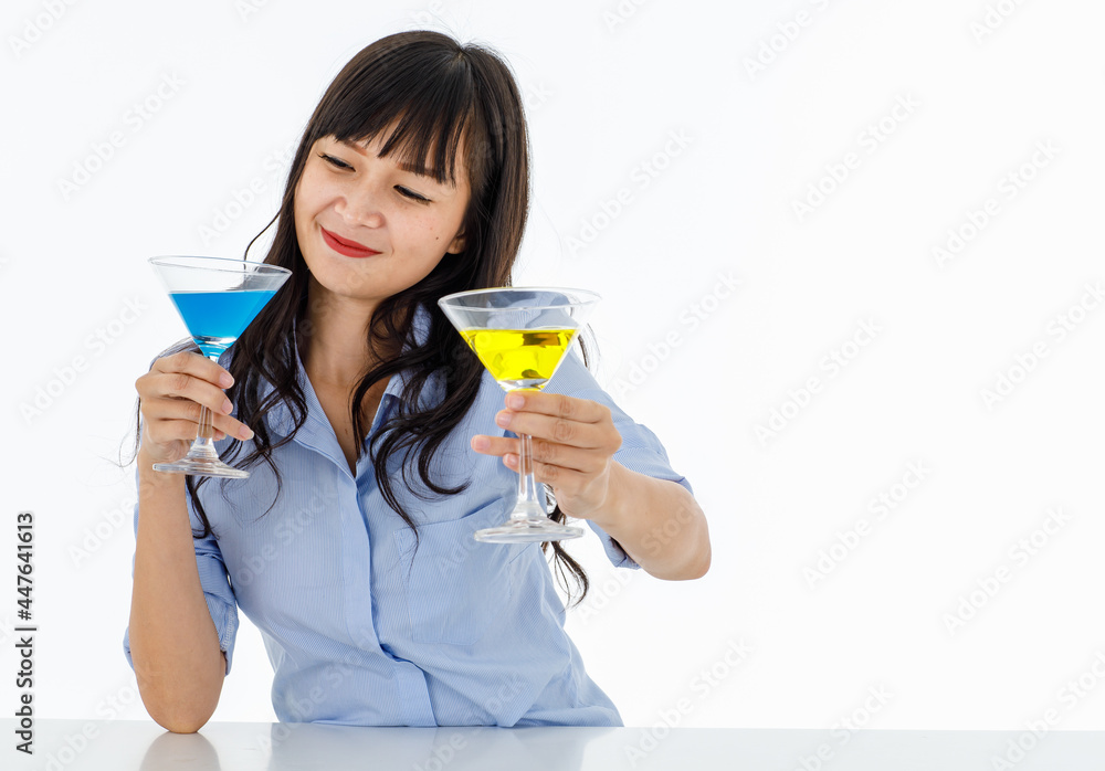 Asia young woman long black hair beautiful smile clinking eyes wear shirt look at glasses. Hands holding cocktail glass one blue other yellow color. Shooting in studio with white background. Asia young woman long black hair beautiful smile clinking eyes wear shirt look at glasses. Hands holding cocktail glass one blue other yellow color. Shooting in studio with white background.