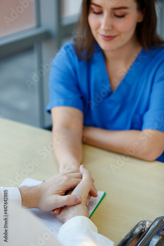 Caucasian doctor holding lady patient hand to support encouragement. Shoot photo to focus to hands