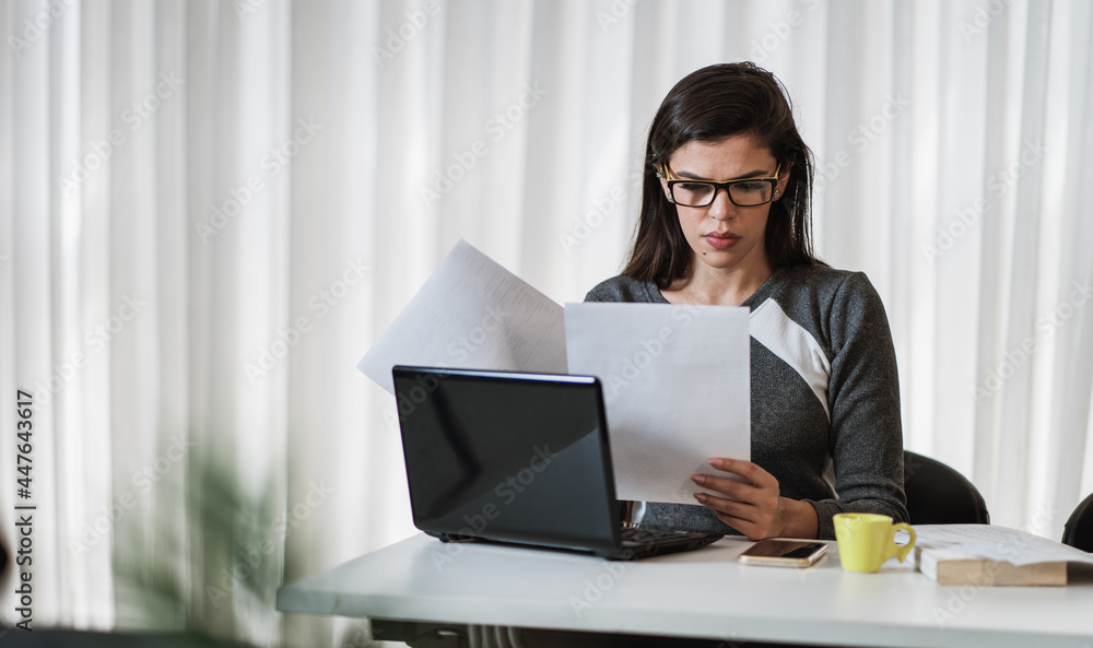 Young beautiful Brazilian woman working with laptop while sitting at office desk, working from home concept. Young beautiful Brazilian woman working with laptop while sitting at office desk, working from home concept.