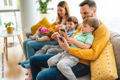 Parents with children playing games, using mobile apps on phone at home