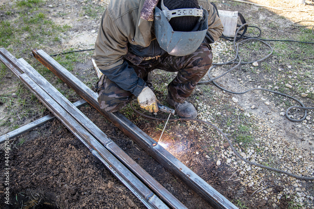 A welder welds metal at a construction site. A welder welds metal at a construction site.