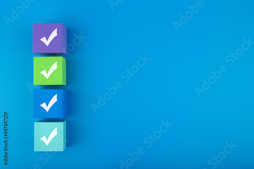 Obraz na płótnie Creative flat lay with multicolored toy blocks with checkmarks on blue background with copy space. Concept of questionary, checklist, to do list, planning or business w salonie