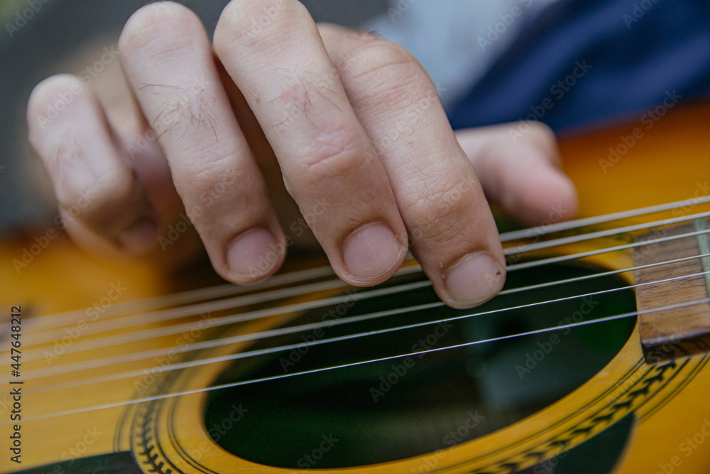 Fototapeta premium close-up of a guitar playing with the fingers of a man's hand playing the strings