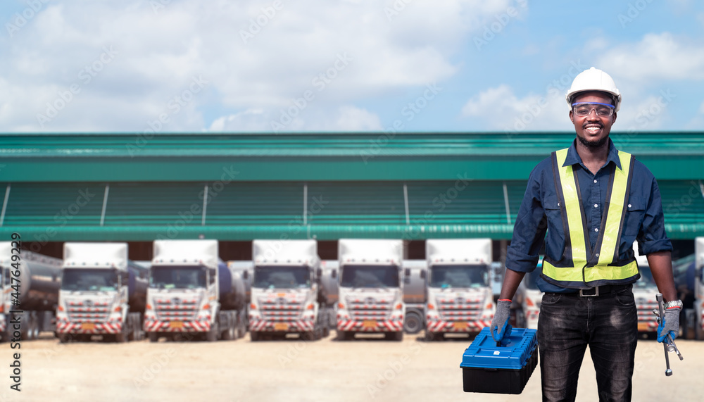 Fototapeta premium African man technician standing against the truck with holding tool box in hands