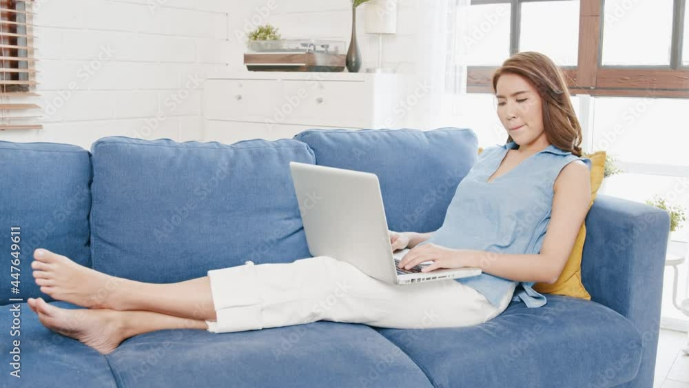 Young Asian Business woman sitting on sofa stretching herself and exercise for relaxation while working hard at home office.. Young Asian Business woman sitting on sofa stretching herself and exercise for relaxation while working hard at home office..