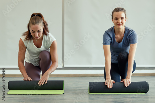 Two women rolling yoga mats after class with happiness