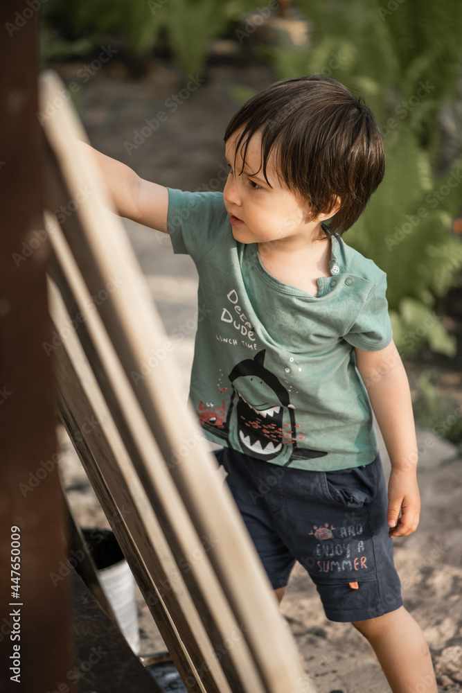 a two-year-old boy paints a wooden fence in the village a two-year-old boy paints a wooden fence in the village
