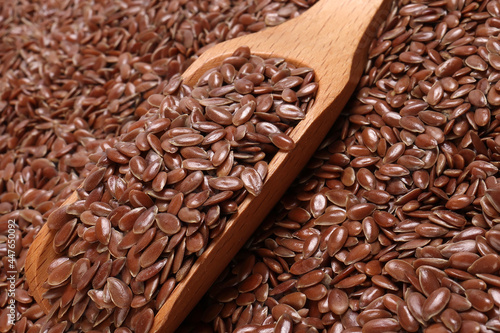 Flex seed flaxseed closeup wooden scoop spoon laid on top with pile of seeds